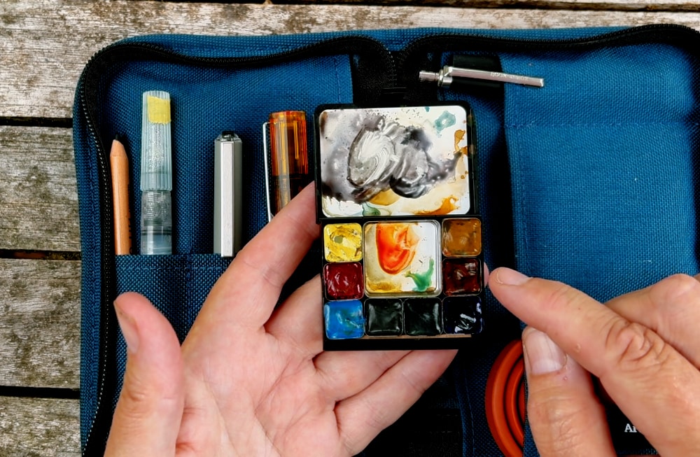 Portable watercolor palette showing eight-color selection for travel sketching